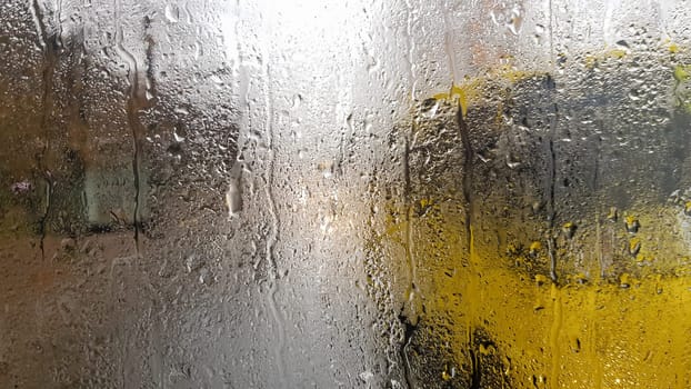 Rain on the rear window of a car in autumn. Inside view of the road with moving cars in the city through the window from the car with rain drops. driving a car in the field of view of the rear window