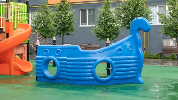 A courtyard of high-rise buildings with a new modern colorful and large playground on a rainy summer day without people. Empty outdoor playground. A place for children's games and sports