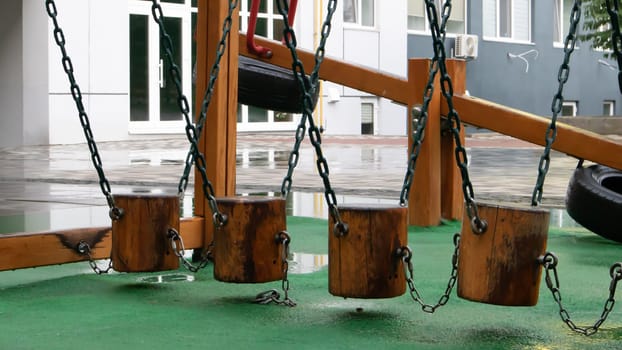 A courtyard of high-rise buildings with a modern and large playground made of wood and plastic on a rainy summer day without people. Empty outdoor playground. A place for children's games and sports
