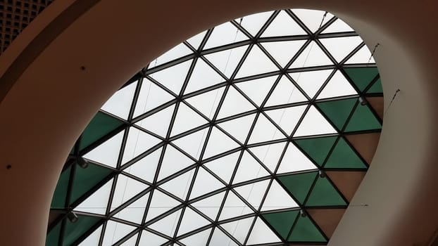 Steel structure roof ceiling made of metal and glass with blue sky background. Modern sleek shopping architecture in mall