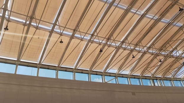 Curved roof with windows of a large shopping center indoors. Modern metal and glass ceiling construction