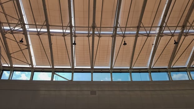 Curved roof with windows of a large shopping center indoors. Modern metal and glass ceiling construction