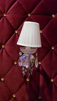 Retro bedroom lamp with a red wall. Antique sconces hanging on a wall of textile with buttons