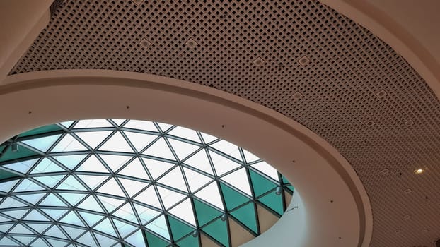 Steel structure roof ceiling made of metal and glass with blue sky background. Modern sleek shopping architecture in mall
