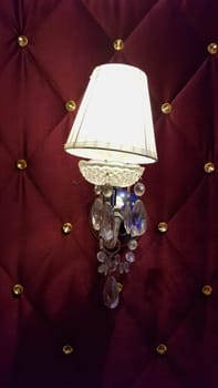 Retro bedroom lamp with a red wall. Antique sconces hanging on a wall of textile with buttons