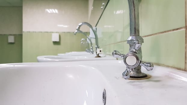 Old and dirty faucet and white ceramic washbasin sink, concept of cleaning, repairing or replacing a bathroom, toilet