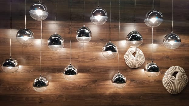 A lot of round lamps near a wooden brown wall. Round lights in the interior. Background for design. Decorative light bulbs