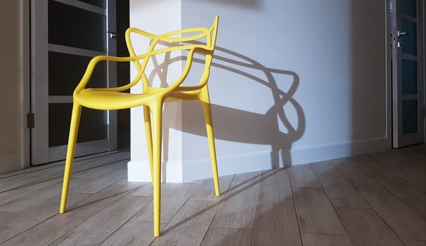 Yellow plastic chair near the wall with a shadow in the interior of the house