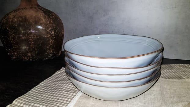 Large glass vases, a basket with apples and plates in the interior of a modern kitchen. The combination of wood and concrete in the design. Modern style dining kitchen.