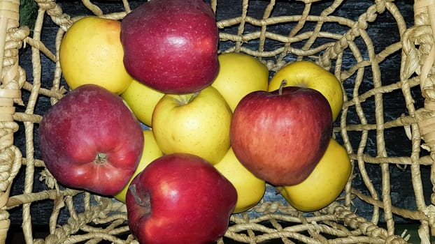 Red and green apples in a basket in a dark key and home decor
