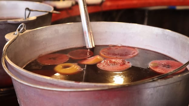 Mulled wine cooked on a fire outside. Vitamins in a winter drink. Street eatery at the Christmas market in winter. Hot mulled wine. Dense steam over cauldrons of hot wine