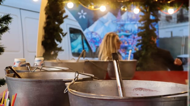 Mulled wine cooked on a fire outside. Vitamins in a winter drink. Street eatery at the Christmas market in winter. Hot mulled wine. Dense steam over cauldrons of hot wine