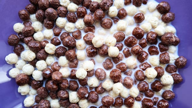 Healthy breakfast with milk on the table in a deep plate. Whole grain chocolate and milk balls. Healthy cereal breakfast. Children's breakfast. Baby food. Balanced diet. Dry ready and quick snack.