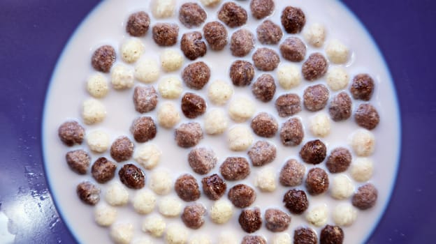 Healthy breakfast with milk on the table in a deep plate. Whole grain chocolate and milk balls. Healthy cereal breakfast. Children's breakfast. Baby food. Balanced diet. Dry ready and quick snack.