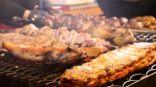 Fried pork ribs. Grilled pork kebabs on a teapot. Barbecue Kid on the grill. grilled kebab, kebab. Festival of delicious fried street food. The meat on the bone, the cooking process.
