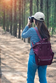 Young female woman lifestyle photographer travel taking photo in forest nature with backpack and copy space.