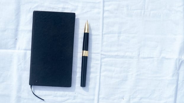 A notebook and a pen on white cotton cloth. High angel view. Business Education background. Copy space room for text on right side.