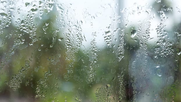Rain drops on glass window. Raindrops falling from glass material. Abstract nature background. Copy space for text. Focus on foreground.
