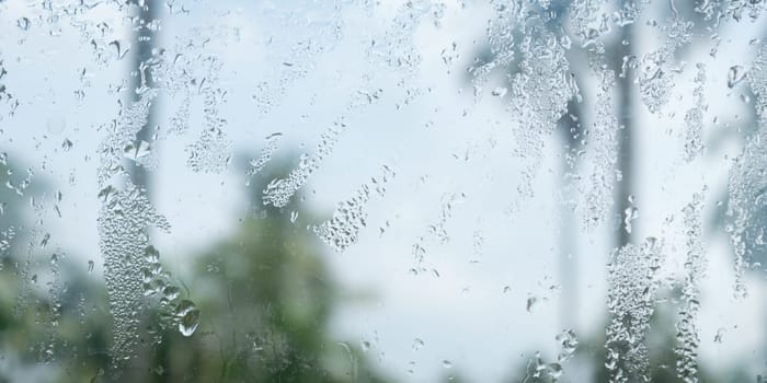 Rain drops on glass window. Raindrops falling from glass material. Abstract nature background. Copy space for text. Focus on foreground.