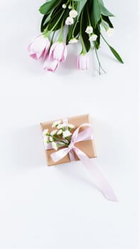 The gift comes in minimalist packaging, decorated with a neutral pink ribbon and flowers symbolizing the arrival of spring. High quality photo