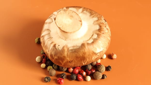 one brown royal champignon on a yellow background with a mixture of peppers. Such mushrooms resemble the taste of porcini mushrooms and have a more pronounced mushroom taste and smell