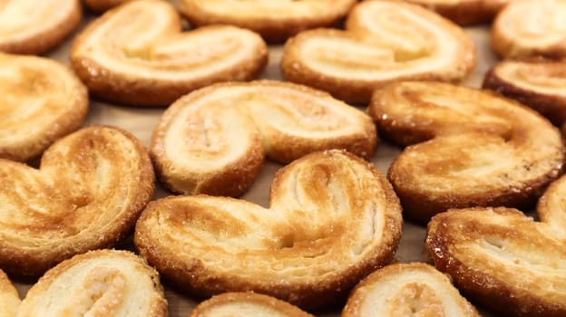 Fresh puff pastry palm cookies in the shape of a heart. Classic French pastries. Pig ear, elephant ear cookies, French hearts. View from above.