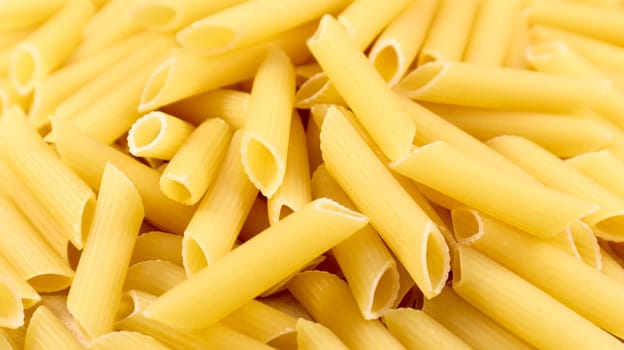 Penne Rigate Raw Pasta is a short pasta with oblique cuts and a ribbed surface. Traditional Italian pasta. Pasta background. Italian food ingredient top view