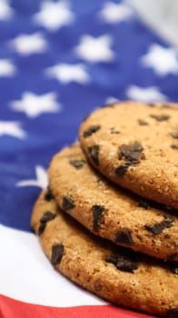 Patriotic cookies. Three rounded traditional chocolate chip cookies on the background of the flag of the United States of America. Delicious sweet pastries, dessert. America's favorite treat