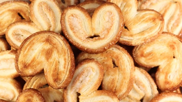 Fresh puff pastry palm cookies in the shape of a heart. Classic French pastries. Pig ear, elephant ear cookies, French hearts. View from above.