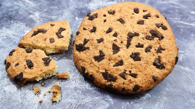 One soft, freshly baked chocolate chip cookie on a gray marble kitchen countertop. American traditional dessert. Delicious sweet food. Homemade baking concept for the holiday. Culinary background.