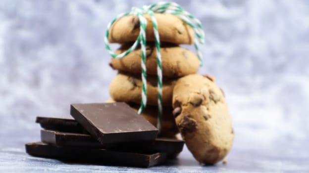 American chocolate chip cookies stacked on top of each other with green thread on a gray background. Traditional rounded crunchy dough with chocolate chips. Bakery. Delicious dessert, pastries