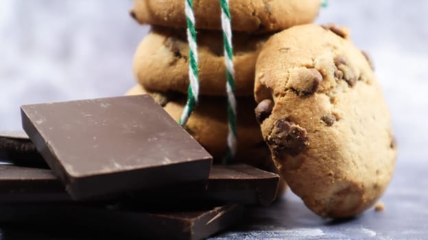 American chocolate chip cookies stacked on top of each other with green thread on a gray background. Traditional rounded crunchy dough with chocolate chips. Bakery. Delicious dessert, pastries