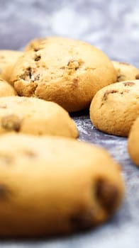 Soft, freshly baked chocolate chip cookies on a gray marble kitchen countertop. American traditional sweet pastry pastry, delicious homemade dessert. Culinary background. Selective focus.