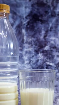 A plastic bottle of fresh regular milk and a glass beaker on a dark gray marbled or concrete background. Close-up front view. World milk day concept. Vertical photography