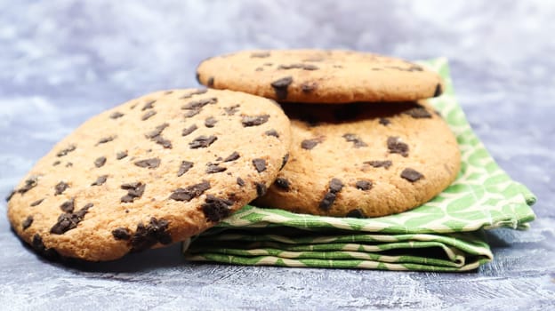 American chocolate chip cookies on a green napkin on a gray background. Traditional round crispy dough with chocolate chips. Bakery. Delicious dessert, pastries