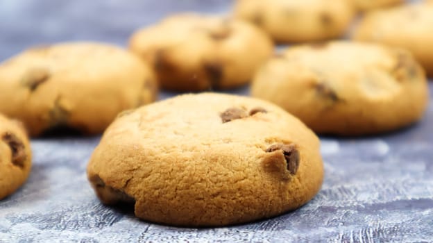 Soft, freshly baked chocolate chip cookies on a gray marble kitchen countertop. American traditional sweet pastry pastry, delicious homemade dessert. Culinary background. Selective focus.