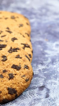 Soft, freshly baked chocolate chip cookies on a gray marble kitchen countertop. American traditional sweet pastry pastry, delicious homemade dessert. Culinary background. Vertical photography.