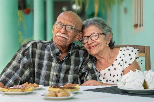 An smiling elderly couple, both wearing glasses.
