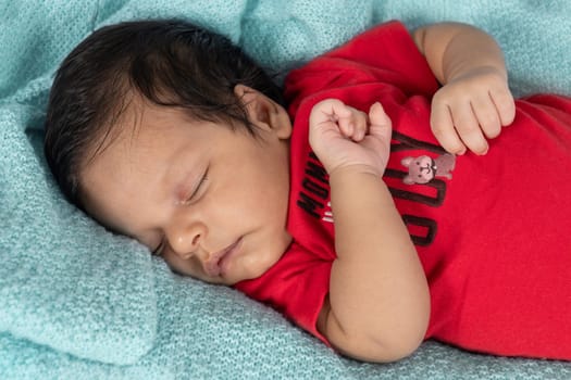 Infant asleep lying on his stomach, dressed in red clothes