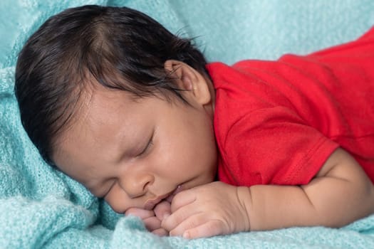 Baby sleeping on his stomach, dressed in red clothes
