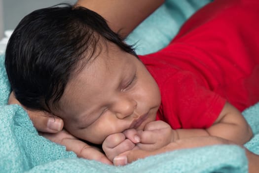 Baby sleeping on his stomach, dressed in red clothes