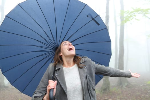 Happy woman with a big umbrella celebrating a rainy day in a park