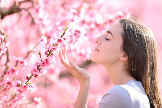 Profile of a woman smelling flowers in a pink field a sunny day