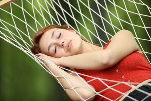 Woman relaxing sleeping on rope hammock in a garden or forest