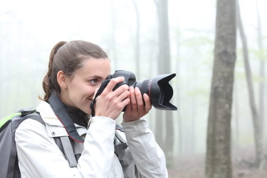 Trekker taking photos with dslr camera in a forest a foggy day
