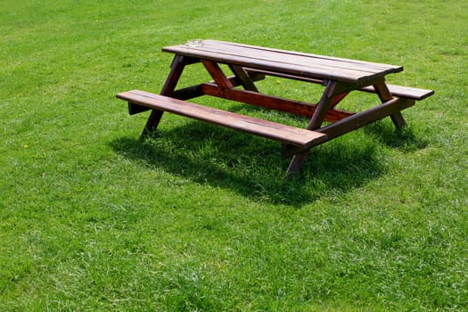 Garden furniture (picnic table - wooden desk and bench in one piece) with ashtray, on a green lawn.