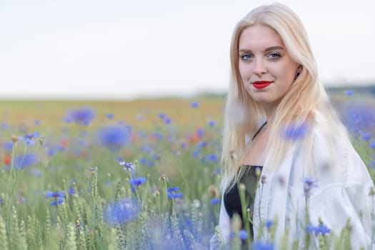 Portrait of attractive blonde woman in cornflower meadow. Horizontally.