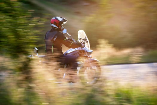 Motorcycle driver driving in beautiful sunset.