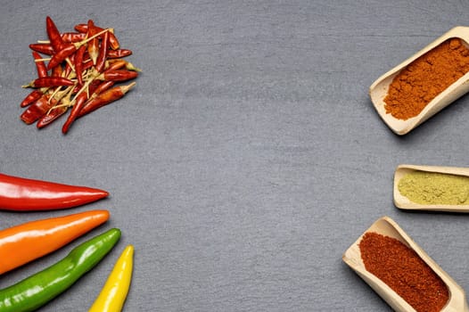 Different types of fresh, dried and ground chili on gray the desk. Horizontally.