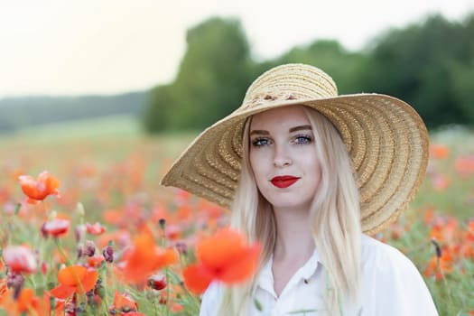 Portrait of blonde young woman in straw hat posing in red poppy looking at the camera.  Horizontally.